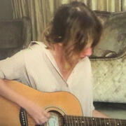 A still from Rep Tour Movie of Taylor Swift playing an acoustic guitar at home